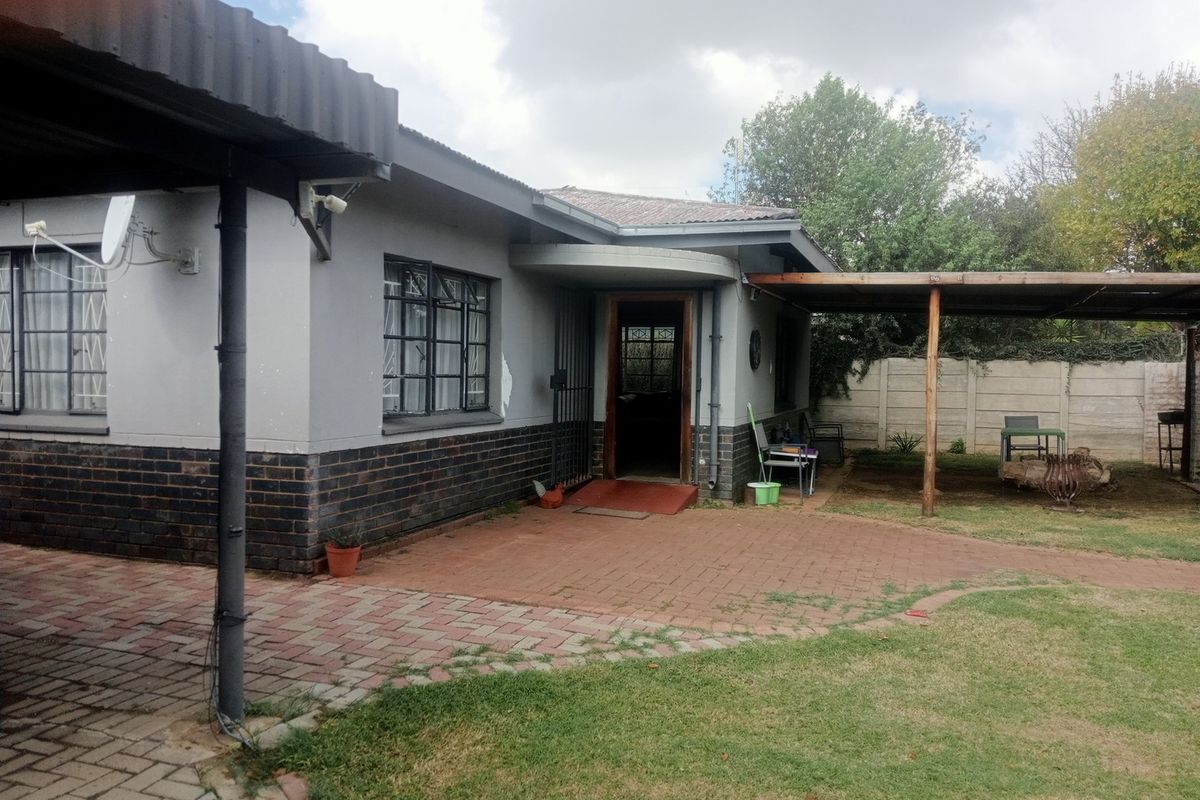 Rear view of the property featuring a paved patio area, covered outdoor space, and a garden enclosed by a precast concrete wall.