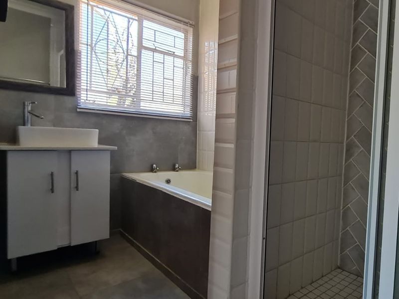 A modern bathroom featuring a vanity with a vessel sink, a built-in bathtub, and a separate shower enclosure with tiled finishes.
