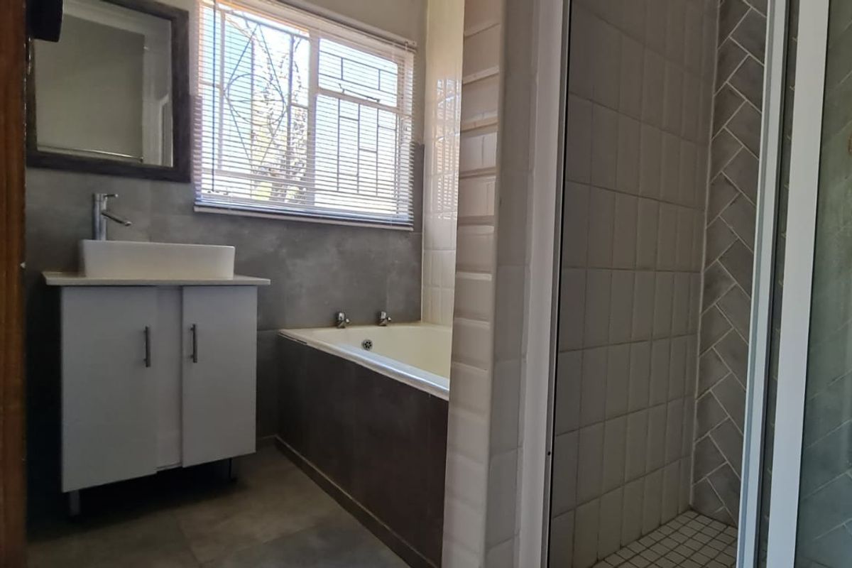 A modern bathroom featuring a vanity with a vessel sink, a built-in bathtub, and a separate shower enclosure with tiled finishes.