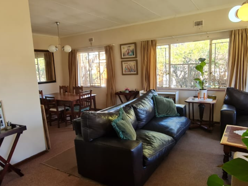 An open-plan living and dining area featuring carpeted flooring and large windows that provide natural light.