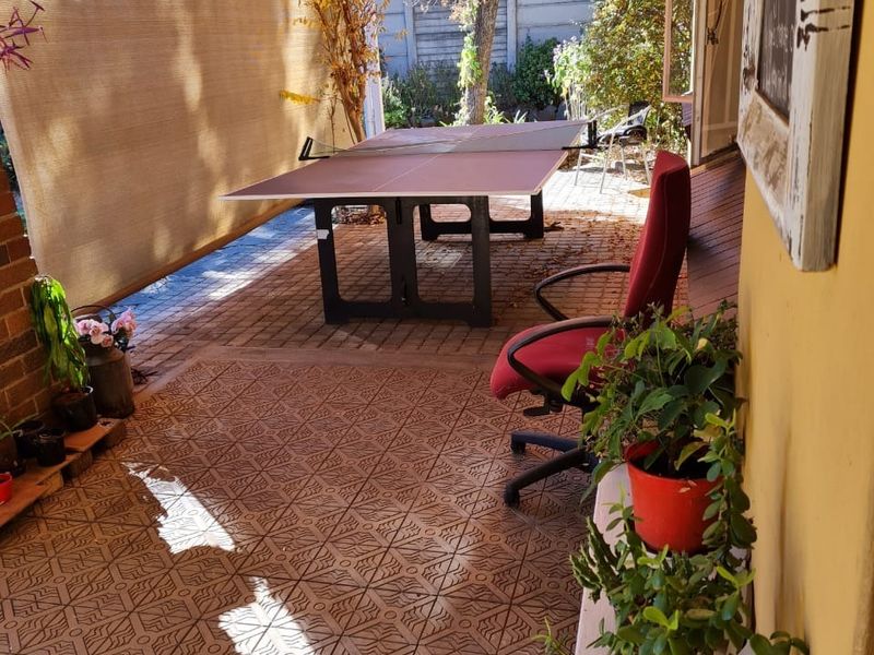 A covered outdoor patio area featuring paved flooring, a brick wall, and a retractable shade screen, providing a functional space for outdoor leisure.