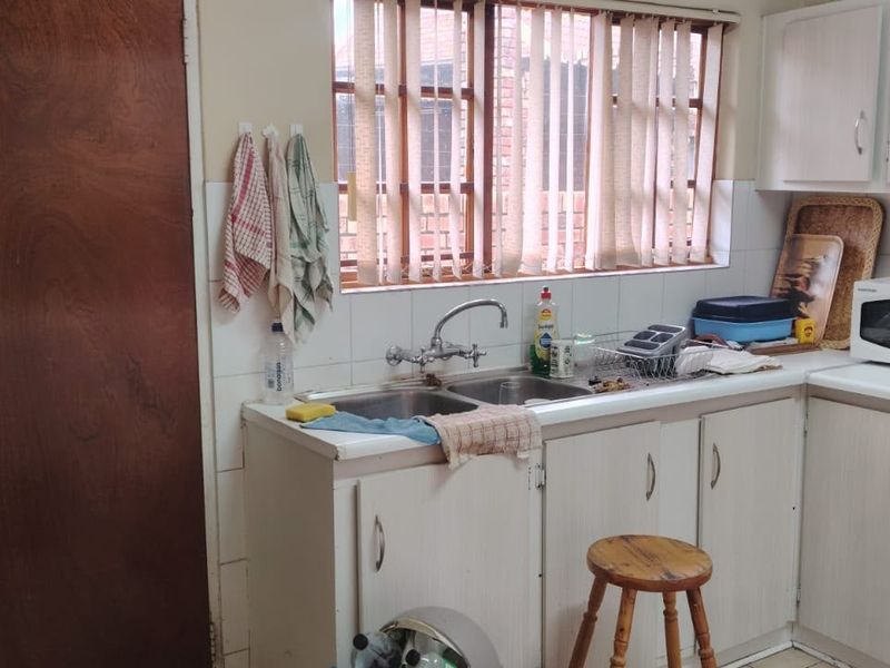 A functional kitchen featuring built-in cabinetry, a double sink, and integrated oven and hob, offering potential for modernization and cosmetic updates.