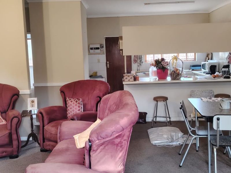 Open plan living and dining area featuring a breakfast bar connecting to the kitchen space with neutral wall finishes and carpeted flooring.