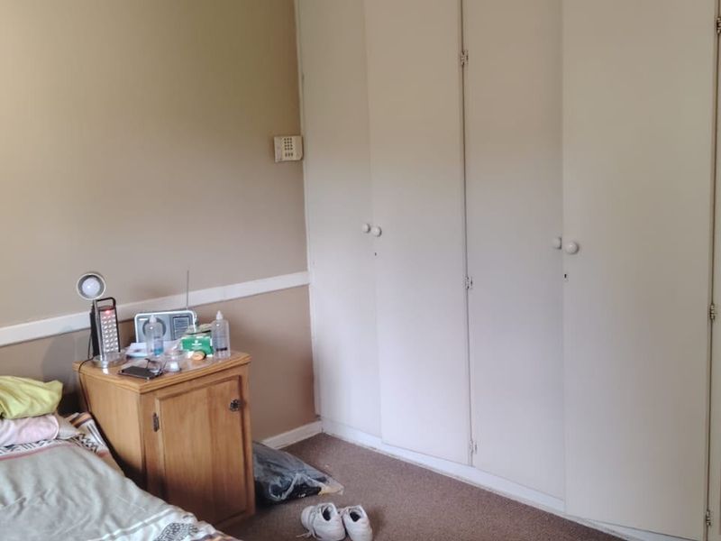 A bedroom featuring built-in cupboards and integrated corner shelving, finished with carpet flooring and a chair rail.