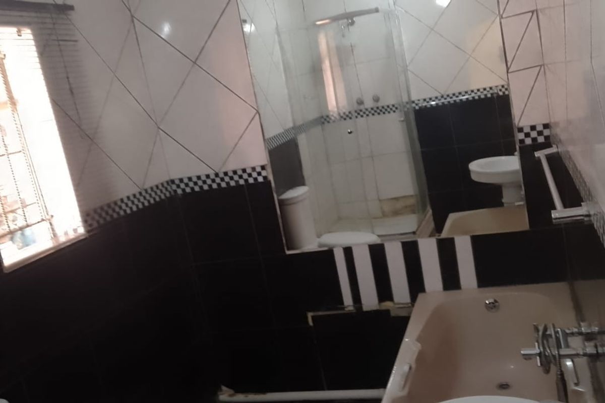 A dated bathroom featuring a bathtub, separate shower enclosure, and pedestal basin with high-contrast black and white wall tiling.