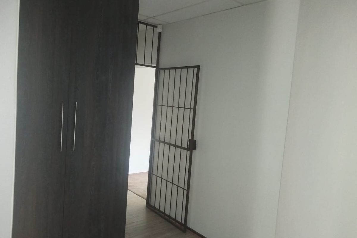 A bedroom featuring laminate flooring, a built-in wardrobe, and a security gate leading to an adjacent space.
