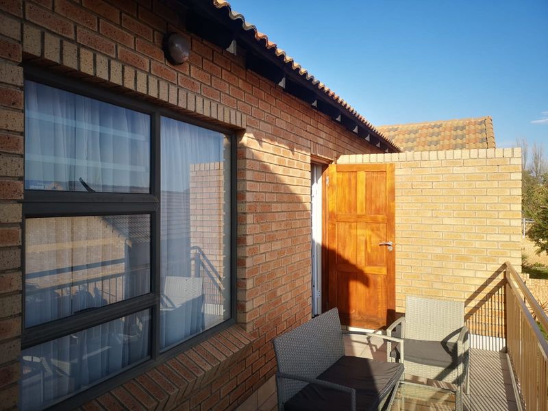 A well-maintained balcony featuring face brick exterior walls, a timber door, and a metal balustrade, providing a functional outdoor space.