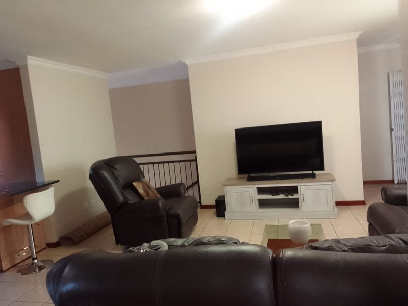 Open plan living area featuring ceramic floor tiles, coved cornicing, and a breakfast bar, providing a functional and connected space for daily living.