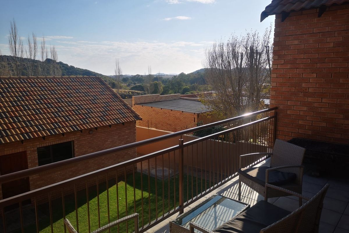 A covered balcony with metal railings, offering elevated views over the surrounding residential area and landscape.