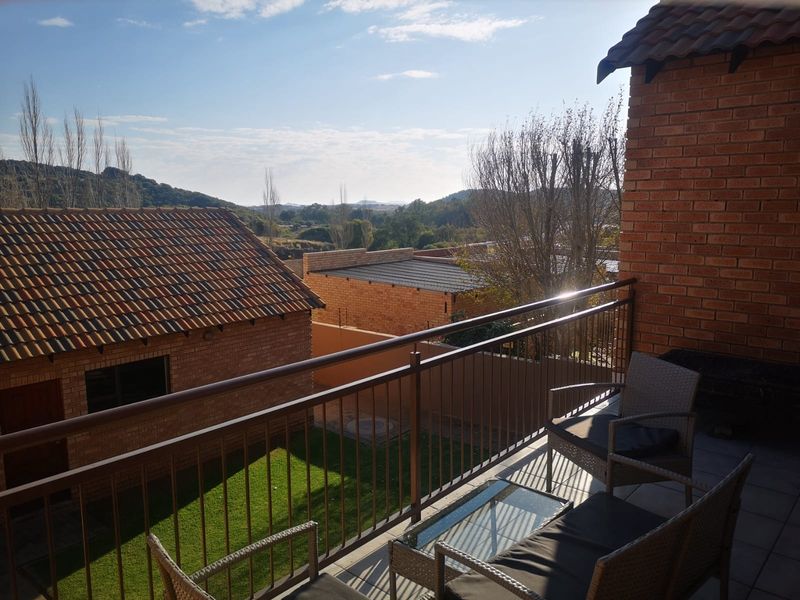A covered balcony with metal railings, offering elevated views over the surrounding residential area and landscape.