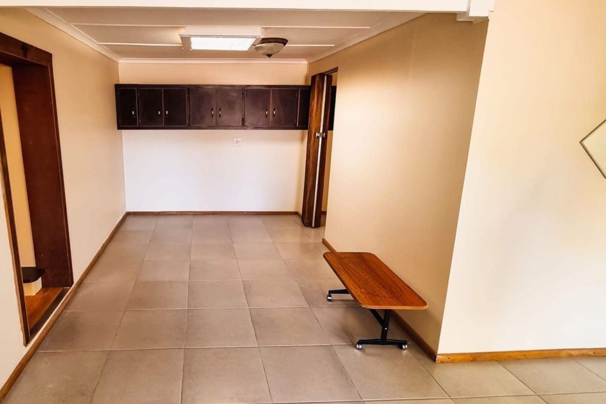 An empty living area featuring neutral tiled flooring, built-in wall-mounted cabinetry, and simple ceiling lighting, offering a blank canvas for interior design.