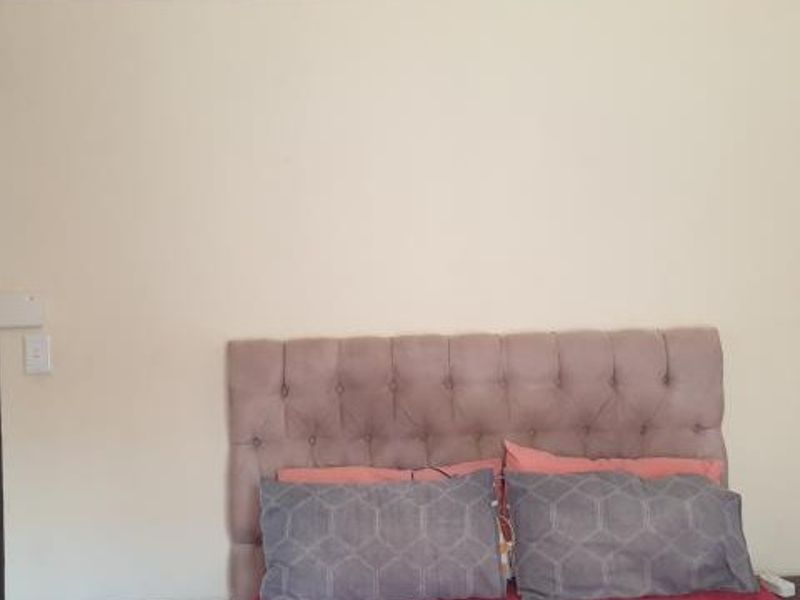 A bedroom interior featuring a neutral wall finish and a view into an adjacent bathroom area.