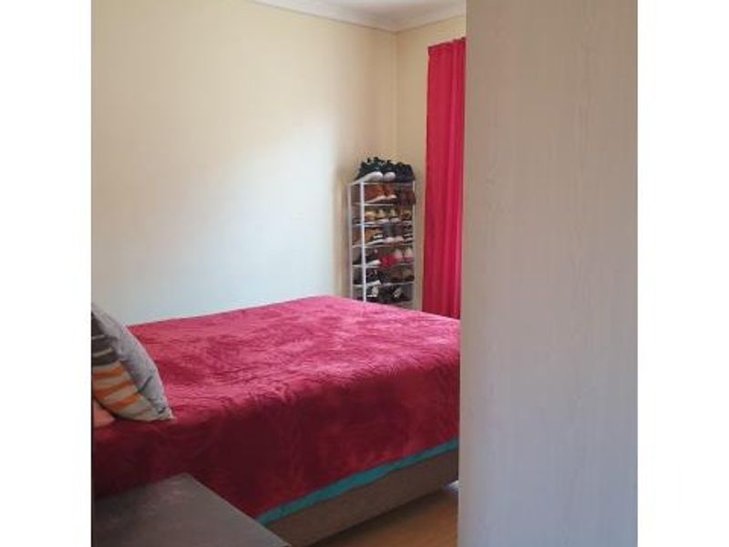 A standard bedroom featuring laminate flooring and coving, providing a functional space for rest.