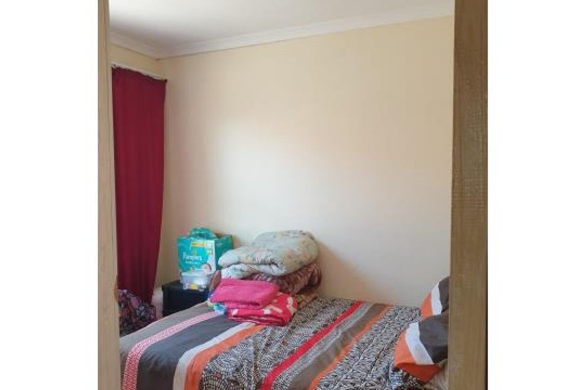 A standard bedroom featuring neutral wall finishes and coving, viewed through a doorway.