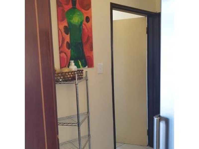 A view of a hallway featuring tiled flooring and a doorway leading to an adjacent room.