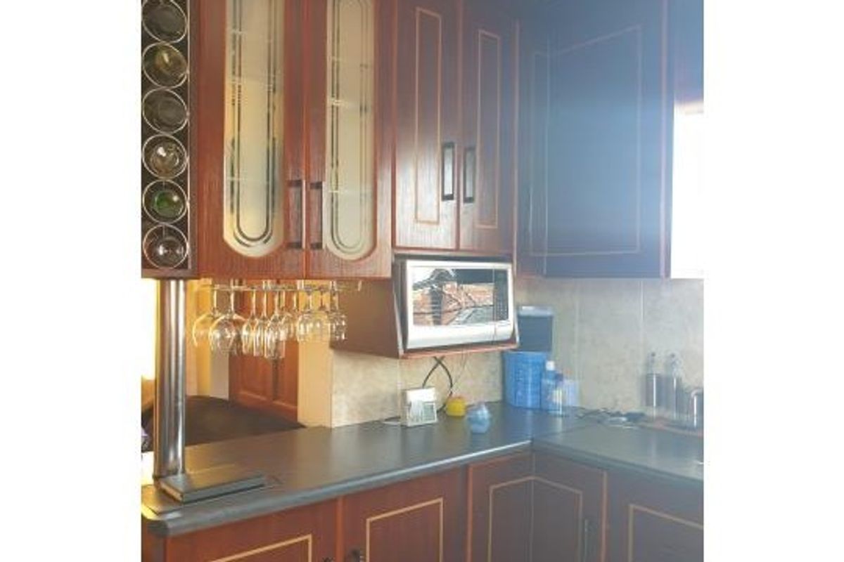 A kitchen featuring traditional wood-finish cabinetry, a built-in microwave, integrated wine storage, and tiled backsplash with ample counter space.