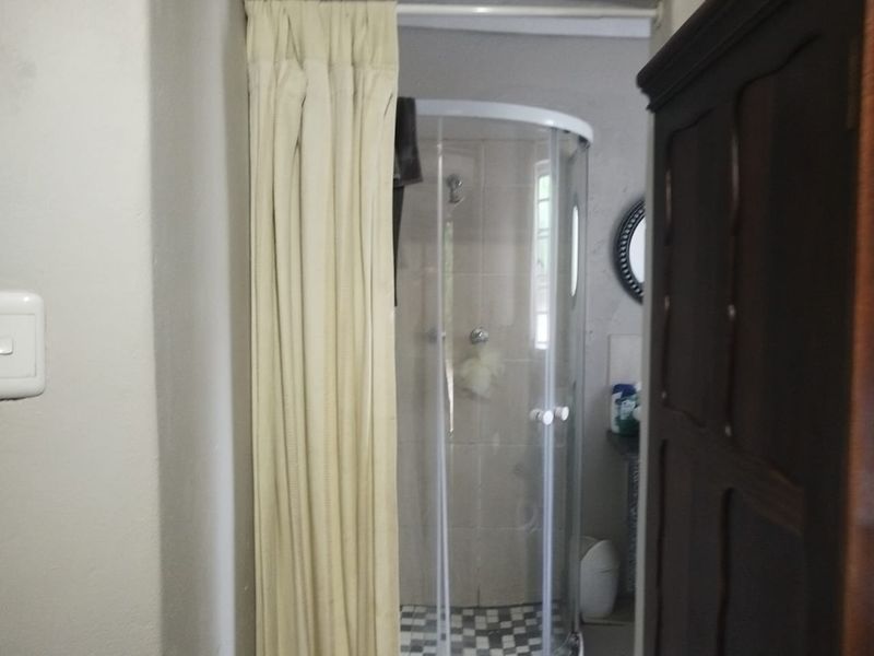 A functional bathroom featuring a corner shower enclosure with tiled flooring and neutral wall finishes.