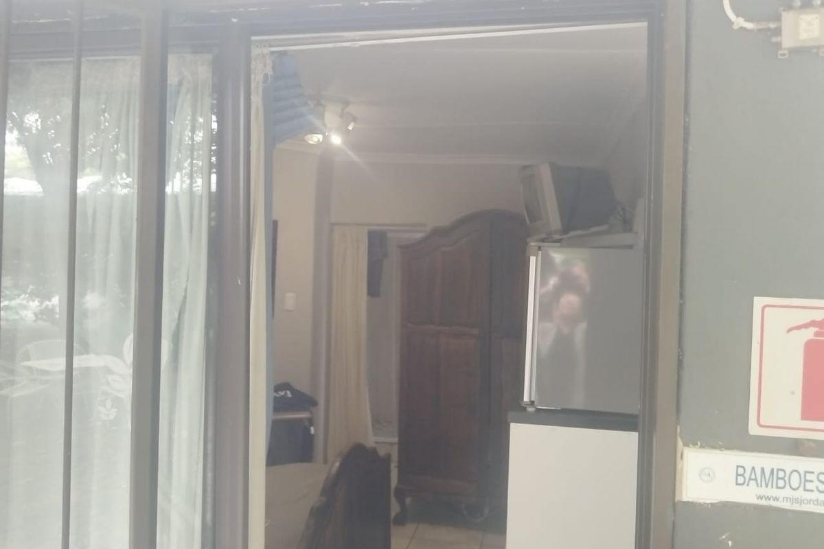 View into a bedroom through a sliding glass door, featuring tiled flooring and basic lighting fixtures.