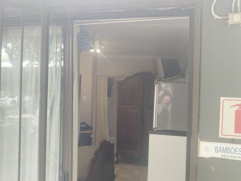 View into a bedroom through a sliding glass door, featuring tiled flooring and basic lighting fixtures.