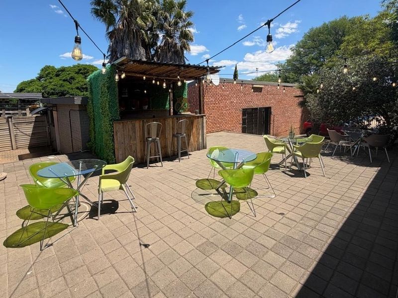 Spacious outdoor patio area featuring a built-in bar, paved flooring, and overhead string lighting, ideal for outdoor entertaining.