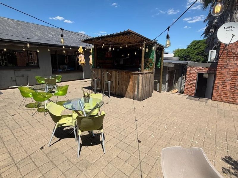 Outdoor paved patio area featuring a built-in bar with a thatched roof, ideal for entertainment and outdoor dining.