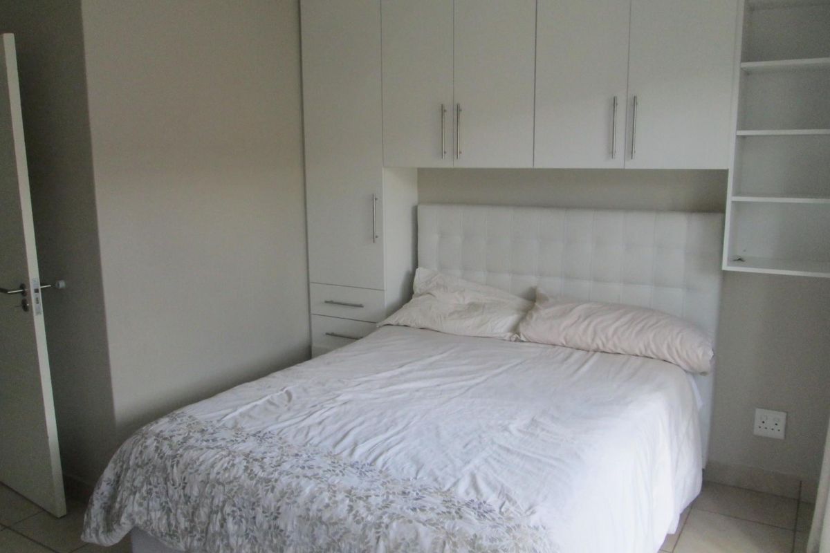 A bedroom featuring white built-in cupboards with integrated shelving and tiled flooring.