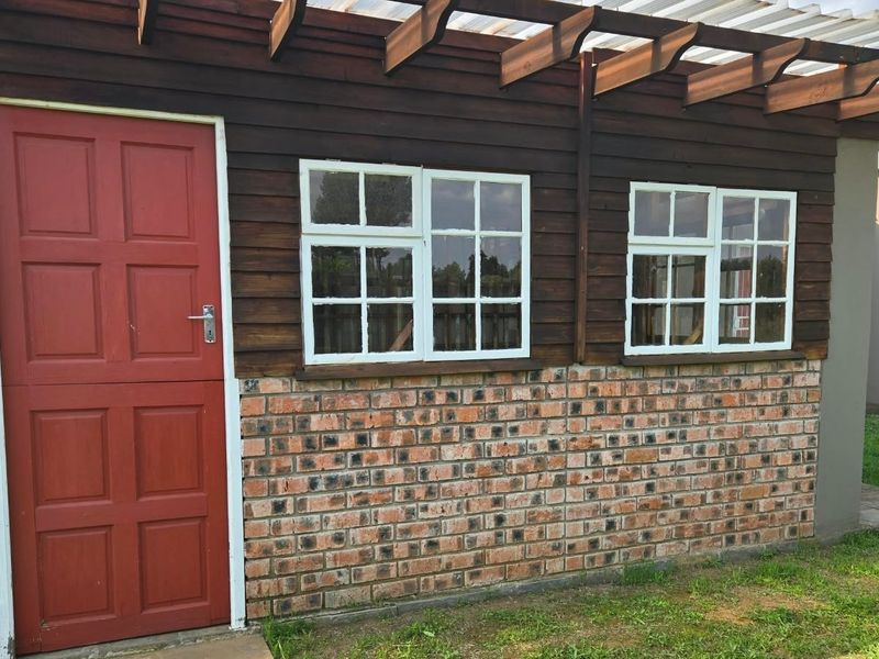 Exterior view of the property featuring a timber pergola, brick base, and timber stable door with classic window frames.