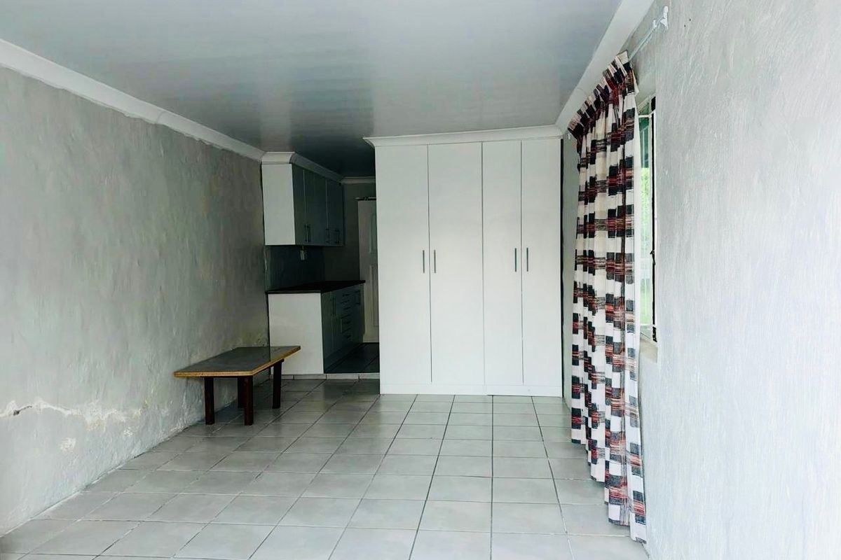 Open plan living area featuring tiled flooring, built-in cupboards, and an adjoining kitchen space with cabinetry.