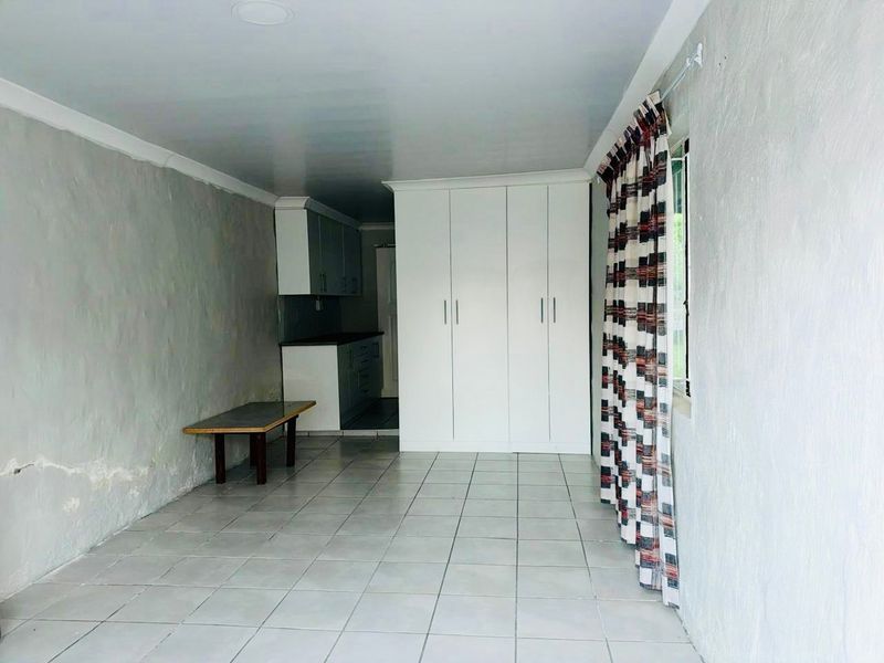 Open plan living area featuring tiled flooring, built-in cupboards, and an adjoining kitchen space with cabinetry.