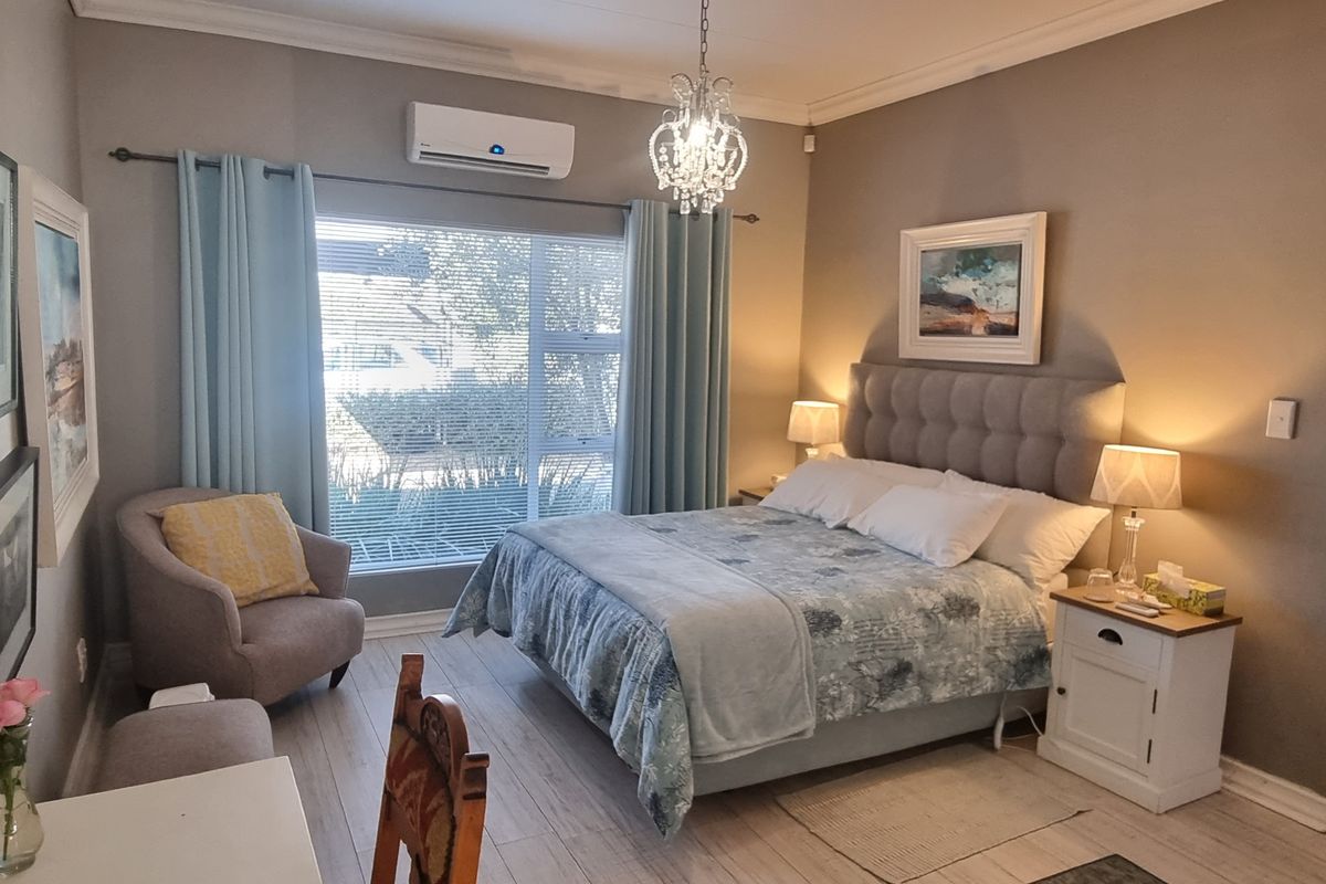 A well-maintained bedroom featuring tiled flooring, a split-system air conditioner, and decorative crown molding, offering a comfortable and functional living space.