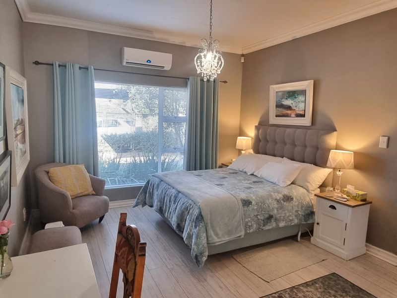 A well-maintained bedroom featuring tiled flooring, a split-system air conditioner, and decorative crown molding, offering a comfortable and functional living space.