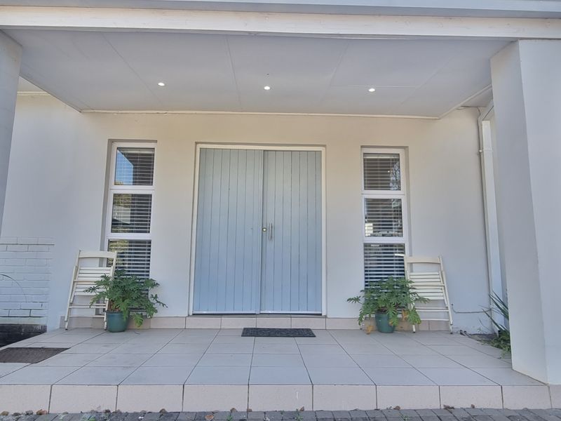 A clean and well-maintained covered front entrance featuring a double door, tiled porch area, and modern recessed ceiling lighting.