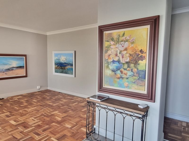 A bright and spacious living area featuring well-maintained parquet flooring, neutral wall tones, and decorative coving.
