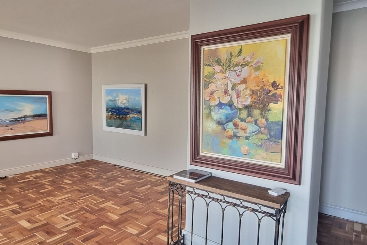 A bright and spacious living area featuring well-maintained parquet flooring, neutral wall tones, and decorative coving.