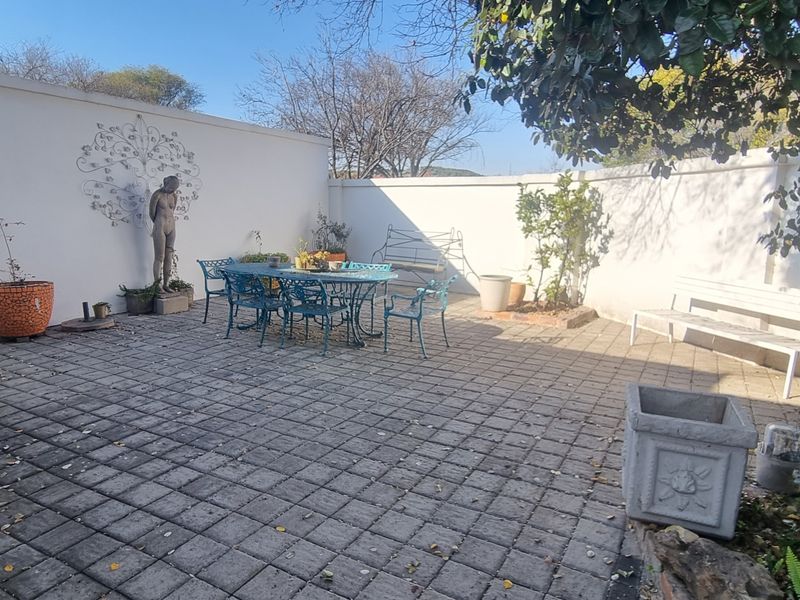 A paved outdoor patio area enclosed by high boundary walls, providing a private space for outdoor dining and relaxation.