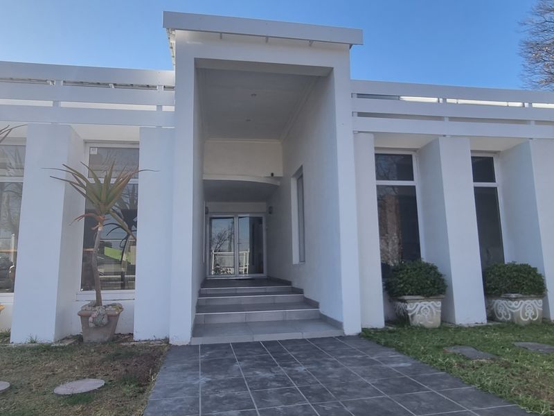 Modern front facade featuring a recessed entrance with tiled steps, large glass windows, and a clean white architectural finish.