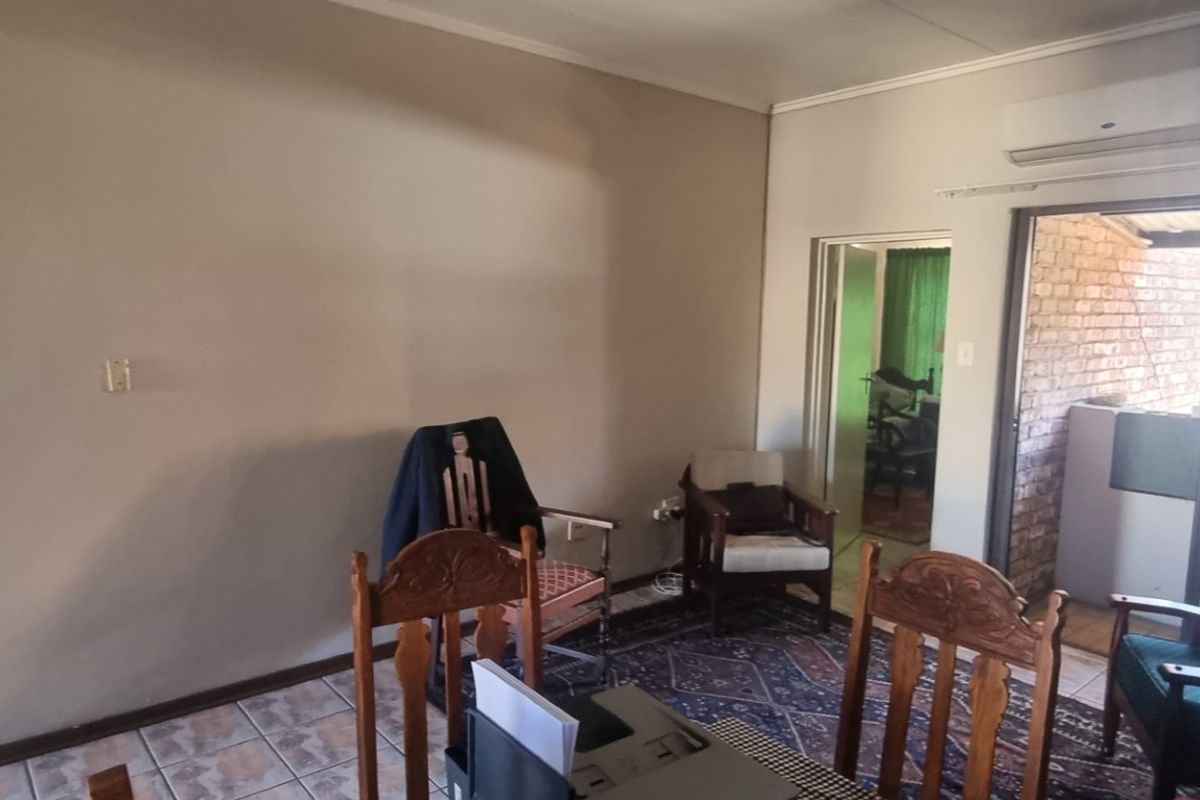 A living area featuring tiled flooring, a wall-mounted air conditioning unit, and direct access to an outdoor patio space.
