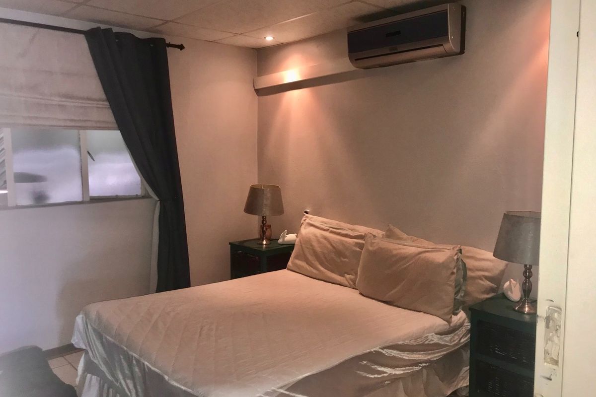 A functional bedroom featuring a wall-mounted split-system air conditioner and recessed ceiling lighting.