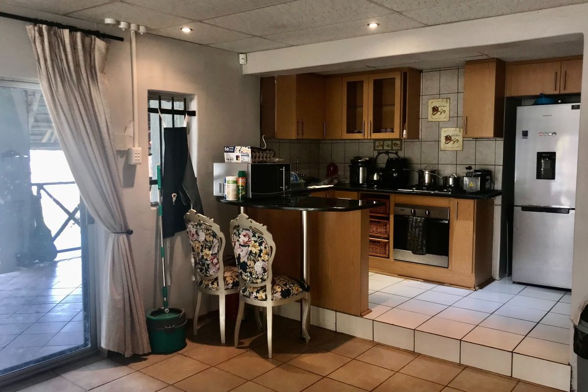A functional kitchen featuring wooden cabinetry, granite countertops, built-in oven, and hob, with a raised floor level and direct access to an outdoor patio area.
