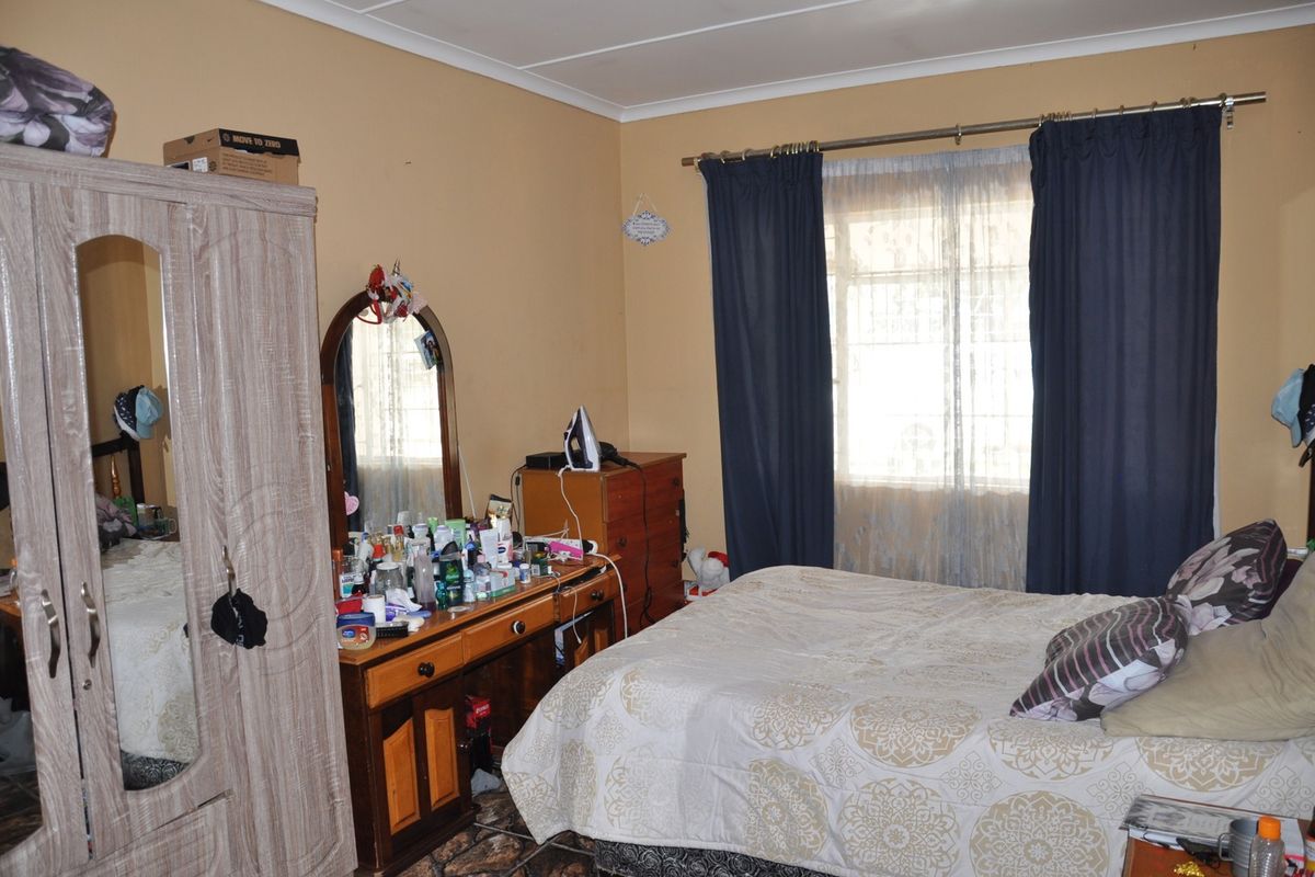 A functional bedroom featuring a window with curtain tracks and tiled flooring, offering a comfortable space for rest.