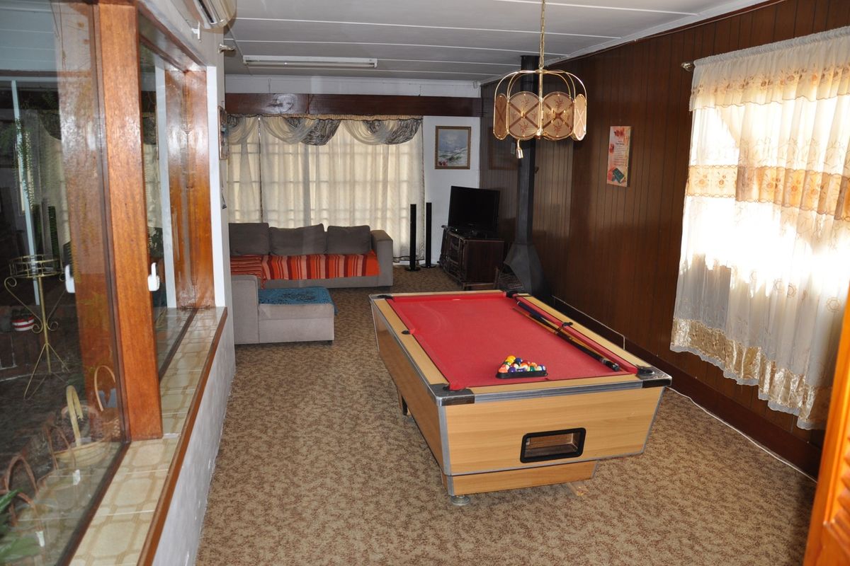 Spacious living area featuring wood paneling, a built-in fireplace, and large windows, currently utilized as a recreational space.