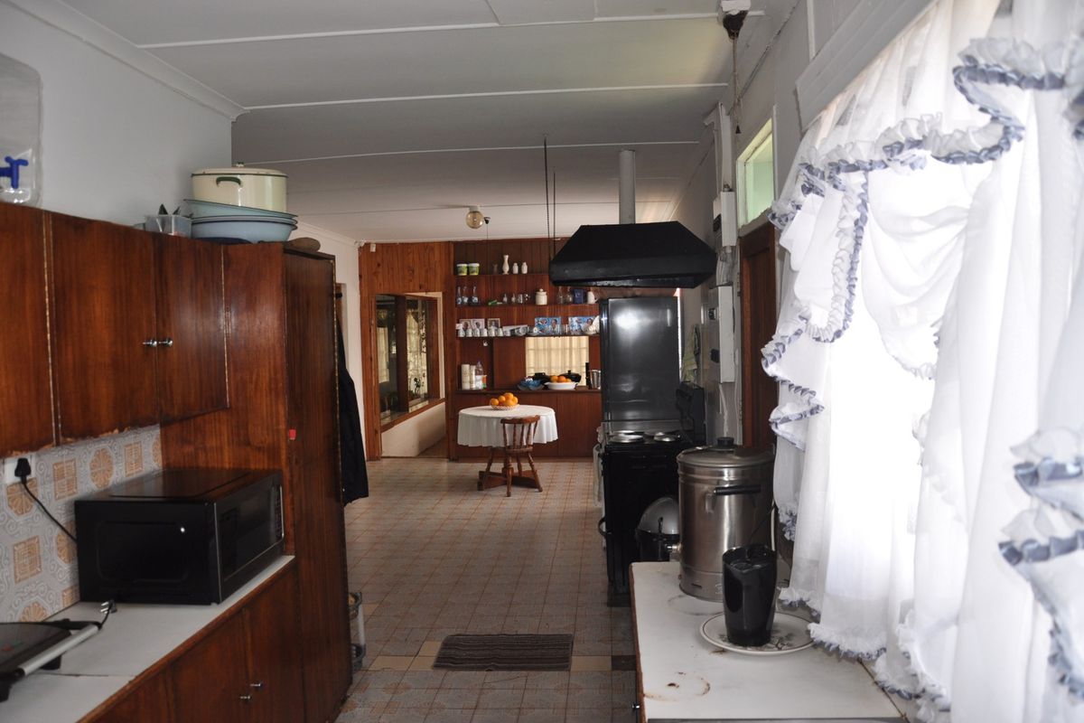 A dated kitchen featuring wood-finish cabinetry, tiled flooring, and a built-in extractor fan, offering a functional layout with potential for modernization.