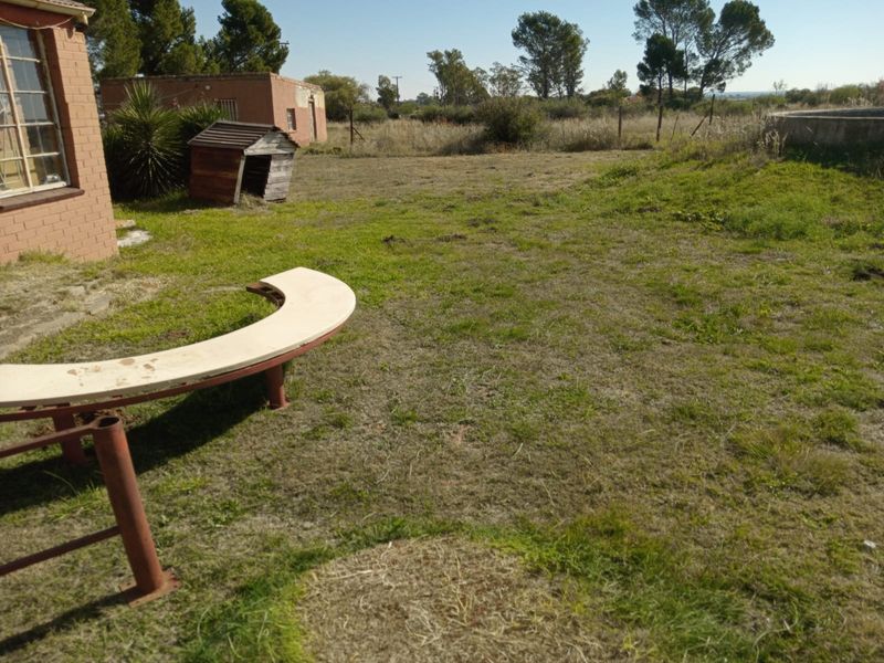 Expansive garden area featuring a small holding outbuilding, established lawn, and a circular concrete water reservoir structure.