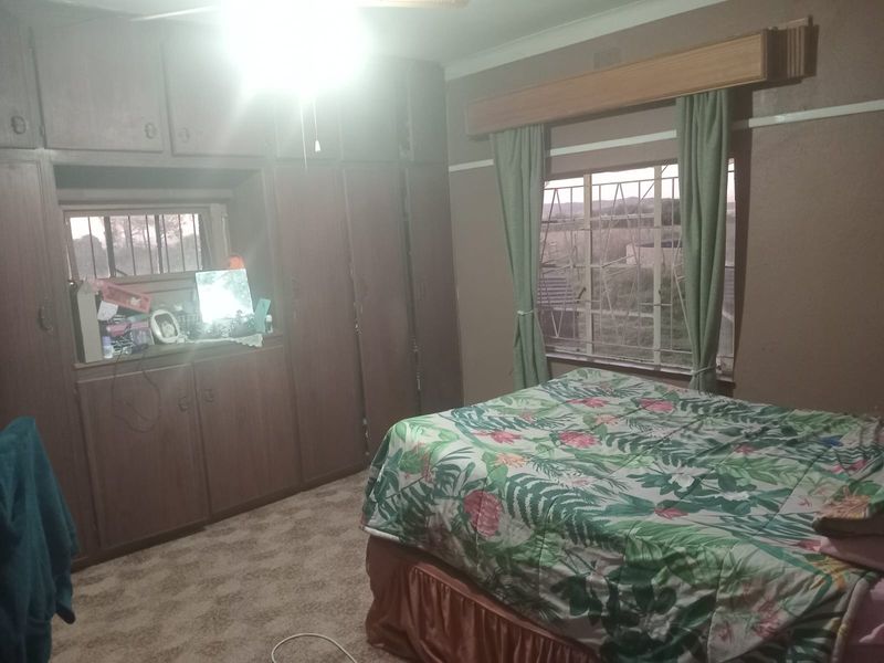 A bedroom featuring extensive built-in wooden cabinetry, carpeted flooring, and security bars on the windows.