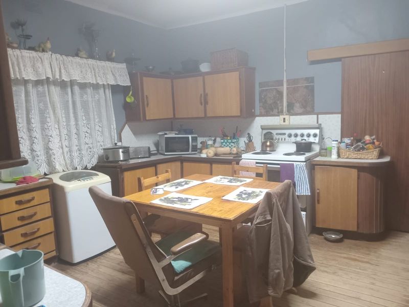 A functional kitchen featuring wooden cabinetry, a freestanding stove, and a dedicated dining area with timber flooring.