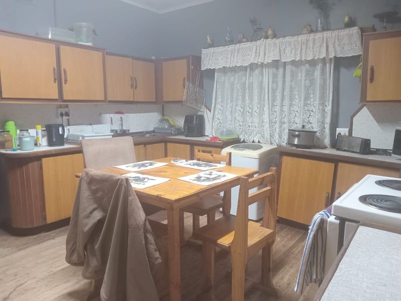 A functional kitchen featuring wooden cabinetry, laminate countertops, and a dedicated dining area, offering a traditional layout with ample storage space.