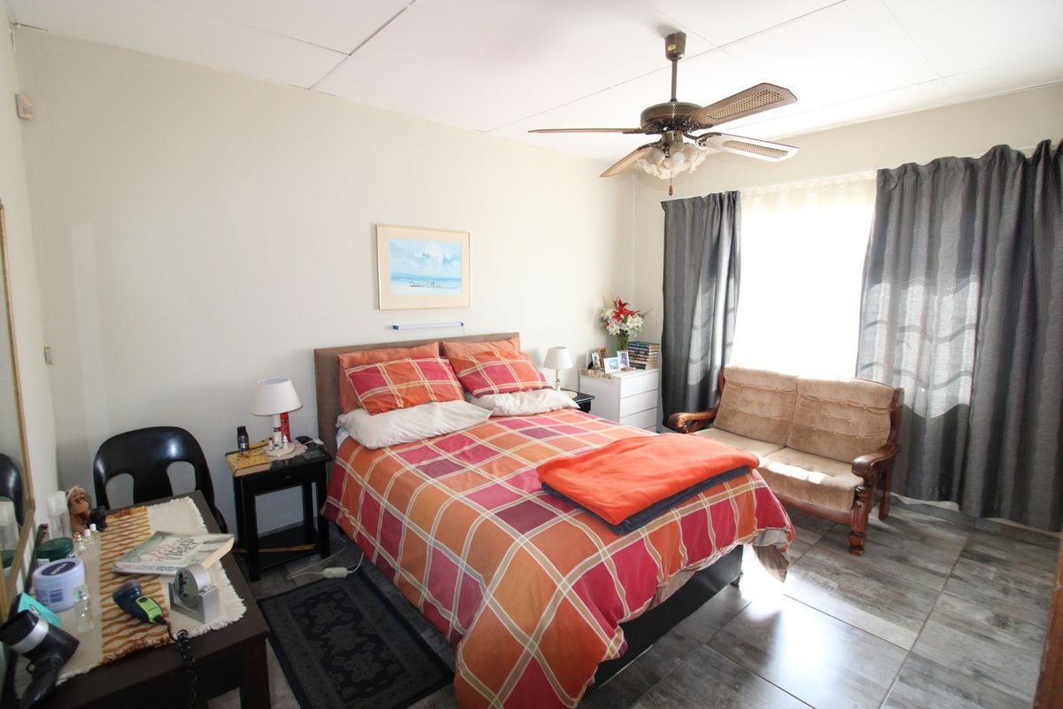 A functional bedroom featuring a ceiling fan and tiled flooring, offering a comfortable space with natural light from the window.