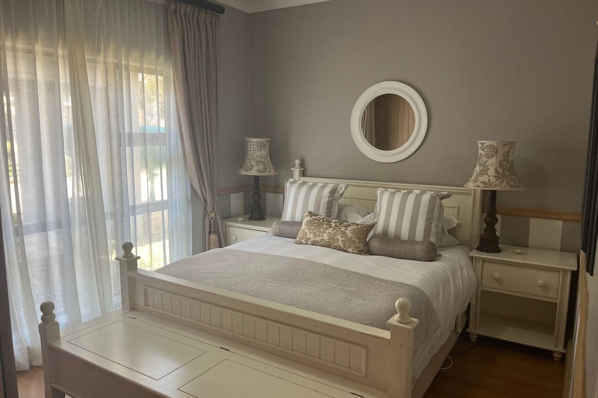 A well-maintained bedroom featuring neutral wall tones, wood-look flooring, and a large sliding glass door providing natural light.