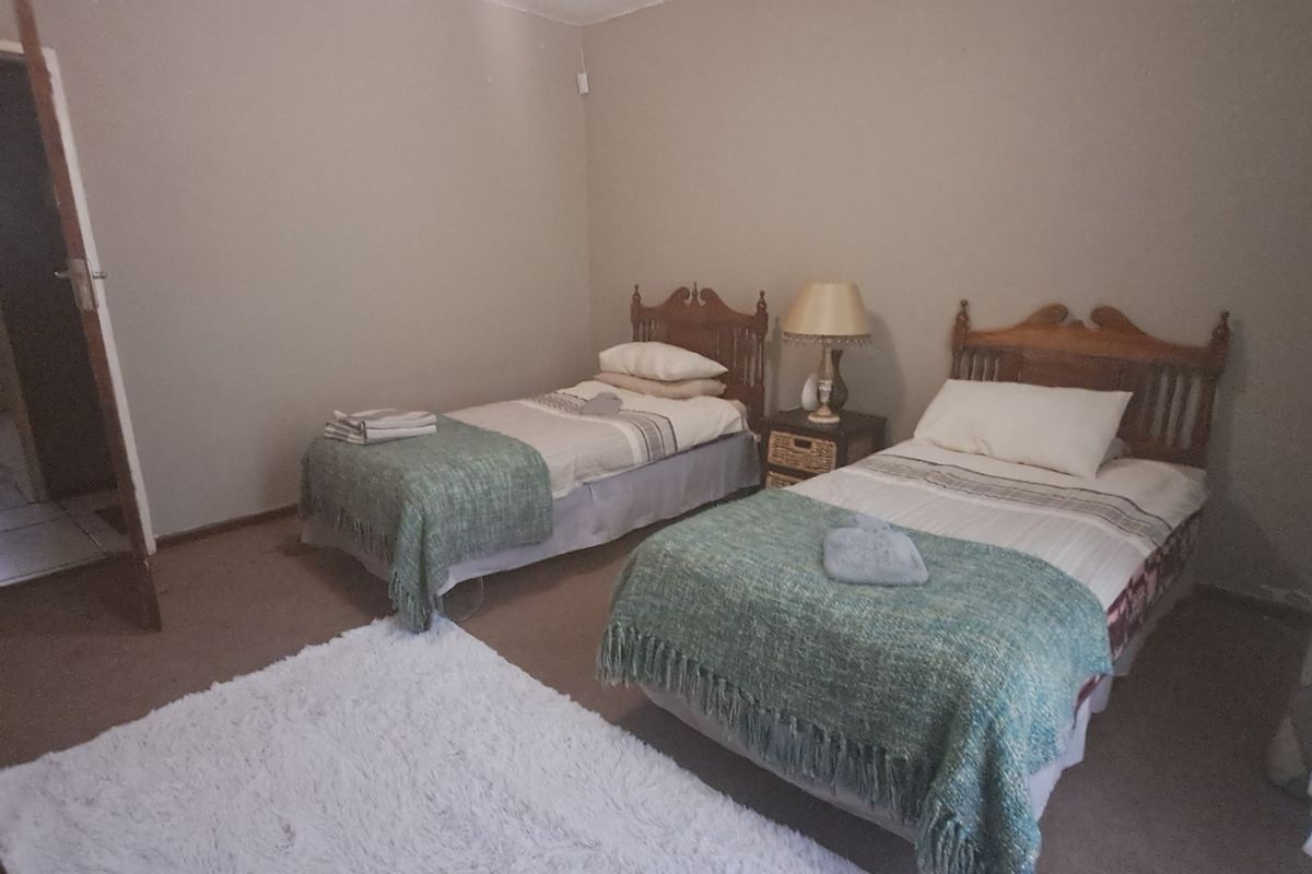 A bedroom featuring neutral wall tones and carpeted flooring, with an adjoining bathroom visible through the doorway.