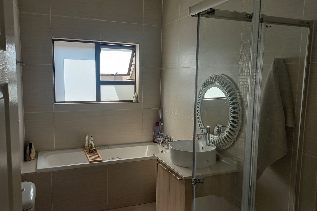 Modern bathroom featuring a built-in bathtub, a separate glass-enclosed shower, and a contemporary vessel sink vanity with neutral wall tiling.